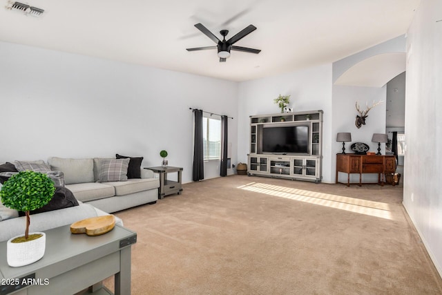 living room featuring visible vents, arched walkways, carpet, and ceiling fan