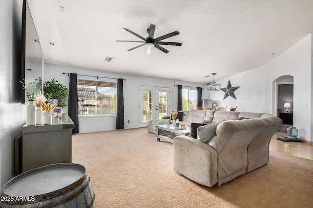 living room featuring visible vents, a ceiling fan, french doors, arched walkways, and carpet