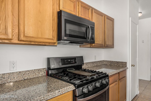 1501 S 122nd Ave, Avondale, AZ 85323 - kitchen with stainless steel range with gas cooktop, light tile patterned flooring, light stone countertops, and brown cabinets