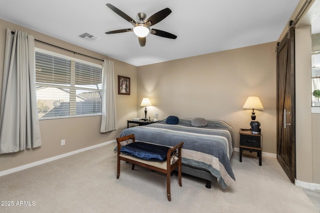 carpeted bedroom featuring a barn door and ceiling fan