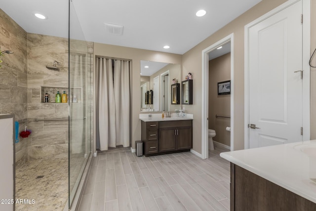 bathroom with vanity, a tile shower, and toilet