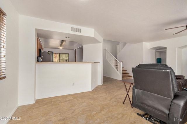 5220 W Desert Ln, Laveen, AZ 85339 - living area with stairway, a ceiling fan, baseboards, and arched walkways
