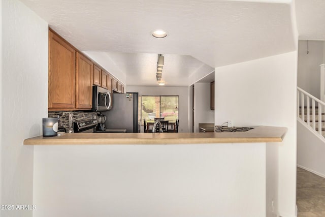 5220 W Desert Ln, Laveen, AZ 85339 - kitchen with appliances with stainless steel finishes, brown cabinets, a peninsula, decorative backsplash, and recessed lighting