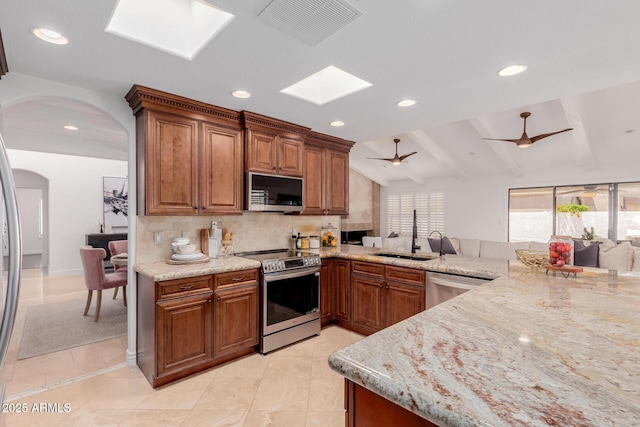 kitchen with backsplash, visible vents, a skylight, a sink, and stainless steel appliances