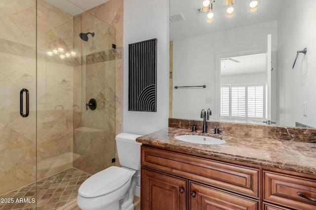 bathroom with toilet, a shower stall, and vanity