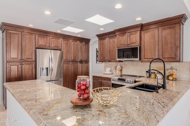 kitchen with appliances with stainless steel finishes, light stone counters, a sink, recessed lighting, and tasteful backsplash