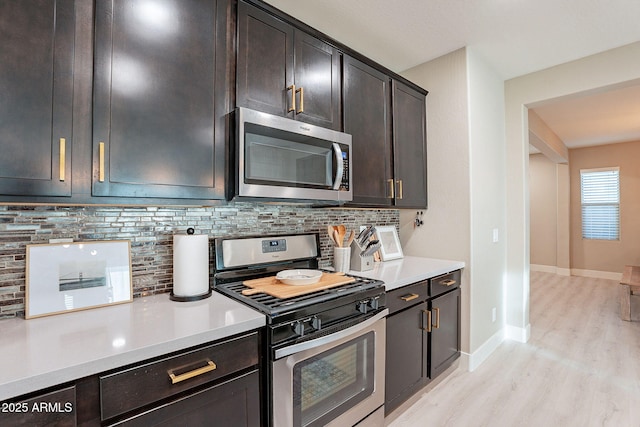 kitchen featuring stainless steel appliances, dark brown cabinets, light hardwood / wood-style flooring, and decorative backsplash