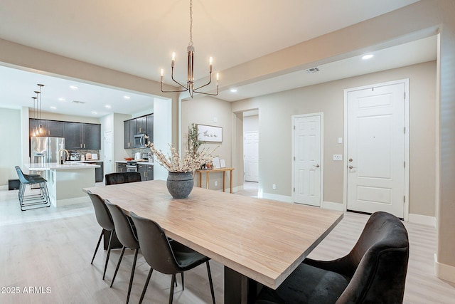 dining space featuring sink, light hardwood / wood-style flooring, and a chandelier