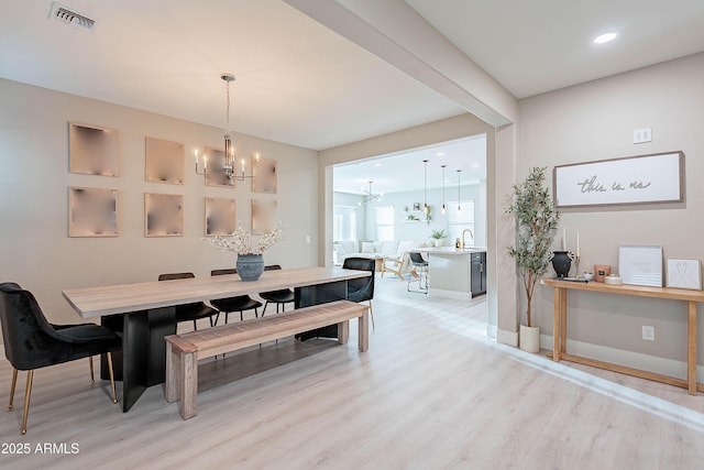 dining area with sink, an inviting chandelier, and light hardwood / wood-style floors