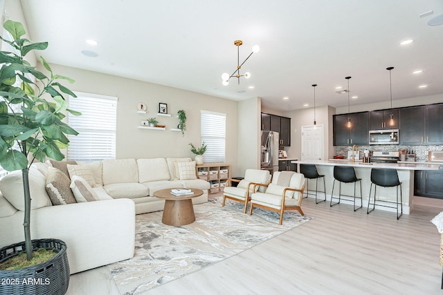 living room with plenty of natural light, sink, and light hardwood / wood-style floors