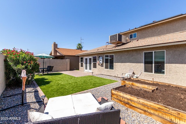 14235 N 26th Ln, Phoenix, AZ 85023 - back of house with stucco siding, a vegetable garden, a fenced backyard, a patio, and french doors