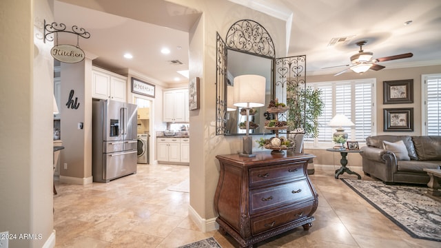 interior space featuring high end refrigerator, washer / clothes dryer, crown molding, white cabinetry, and ceiling fan