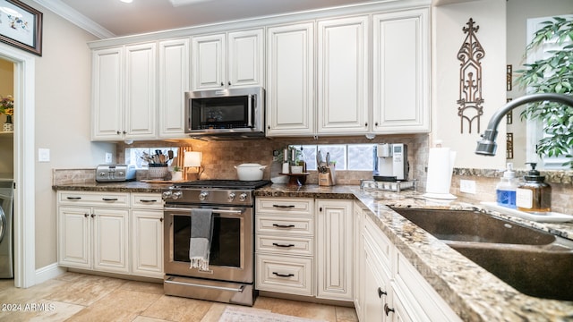 kitchen with stone counters, appliances with stainless steel finishes, sink, white cabinets, and crown molding