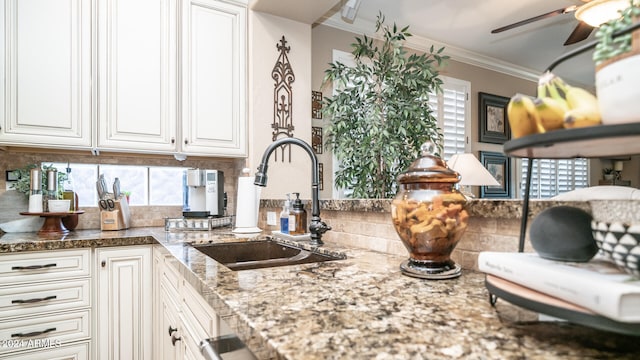 kitchen featuring sink, white cabinetry, crown molding, and backsplash