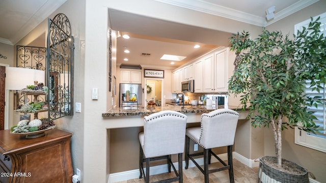 kitchen with kitchen peninsula, a kitchen breakfast bar, dark stone countertops, crown molding, and stainless steel appliances