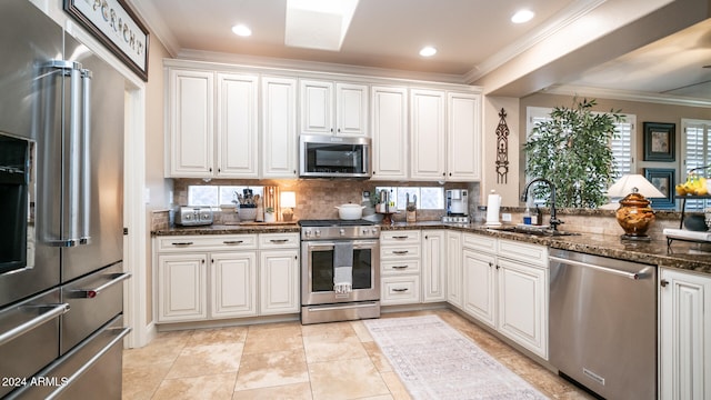 kitchen featuring white cabinetry, dark stone countertops, appliances with stainless steel finishes, and sink