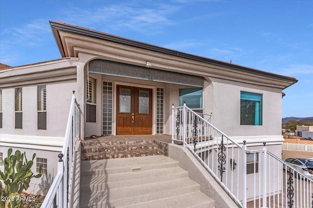 view of exterior entry with a porch and french doors