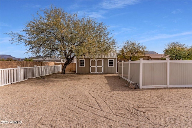 exterior space featuring a fenced backyard, a storage unit, a mountain view, and an outbuilding