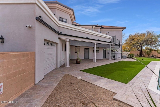 rear view of property featuring a patio, fence, stairway, a lawn, and stucco siding