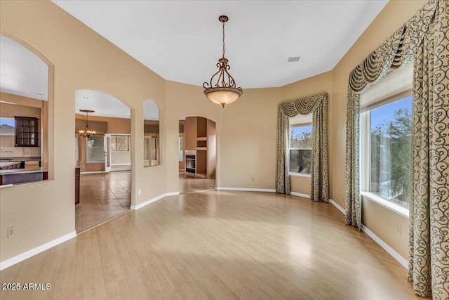 interior space featuring light wood finished floors, baseboards, visible vents, and arched walkways