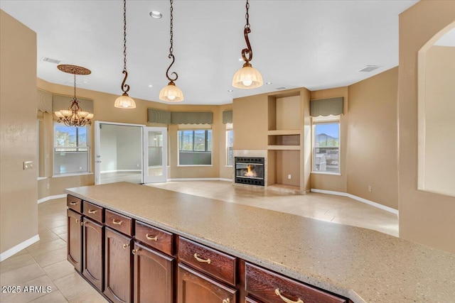 kitchen featuring a warm lit fireplace, light tile patterned floors, visible vents, open floor plan, and pendant lighting