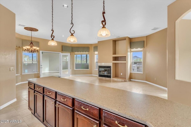 kitchen featuring decorative light fixtures, heating unit, visible vents, open floor plan, and a tile fireplace