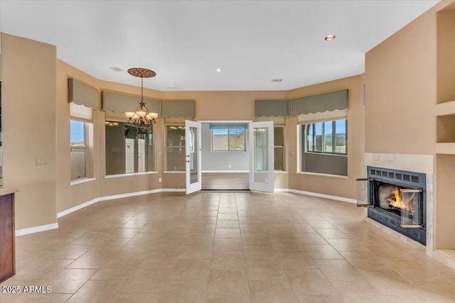 unfurnished living room featuring a chandelier, a premium fireplace, light tile patterned flooring, and baseboards