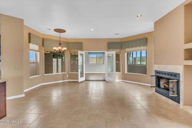 unfurnished living room featuring a notable chandelier, a fireplace, baseboards, and light tile patterned flooring