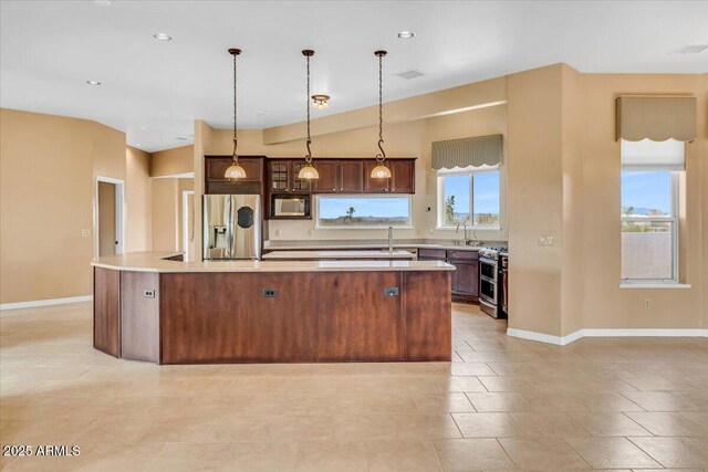 kitchen with hanging light fixtures, a center island with sink, stainless steel appliances, and light countertops