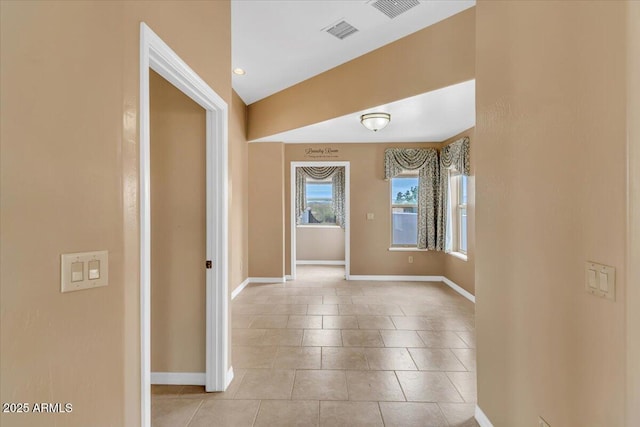 corridor featuring light tile patterned flooring, visible vents, and baseboards