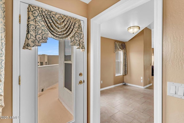 hall with light tile patterned flooring and baseboards