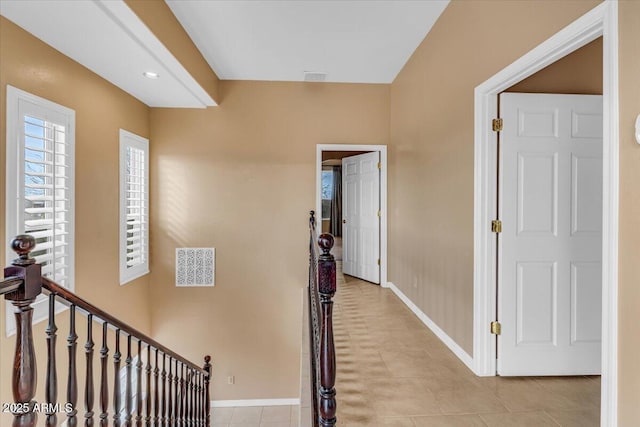 corridor featuring an upstairs landing, light tile patterned flooring, visible vents, and baseboards