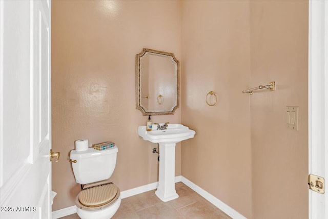 half bathroom featuring toilet, baseboards, and tile patterned floors