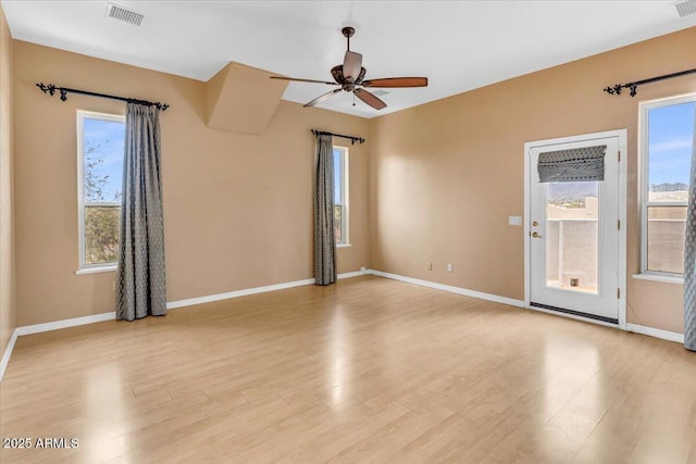 unfurnished room featuring light wood-type flooring, a healthy amount of sunlight, visible vents, and a ceiling fan