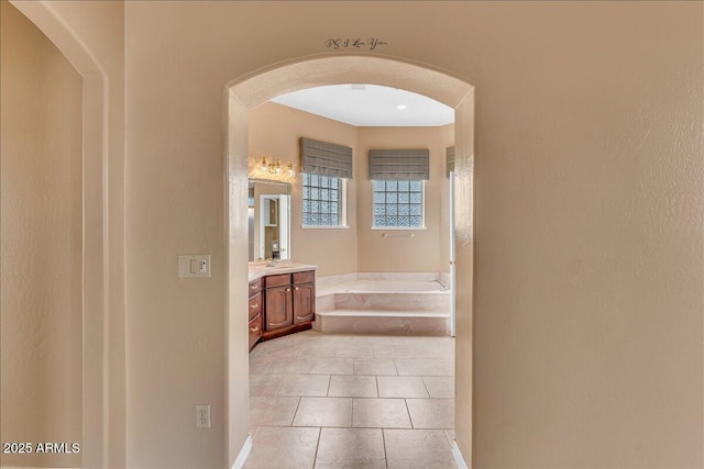 hall featuring arched walkways and light tile patterned flooring