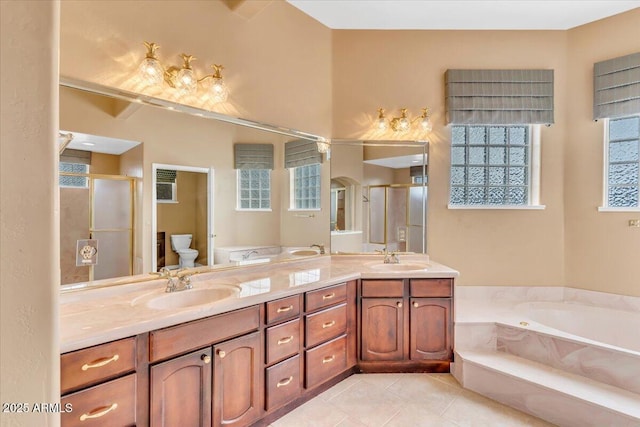 bathroom featuring toilet, a stall shower, a sink, and tile patterned floors