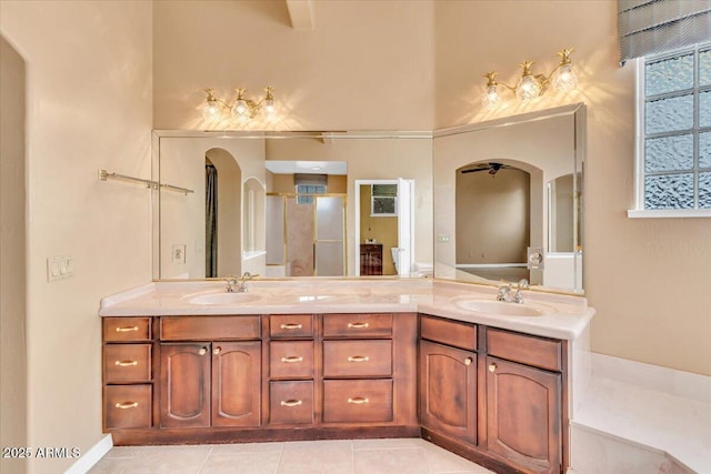 bathroom with tile patterned flooring, a sink, a shower stall, and double vanity