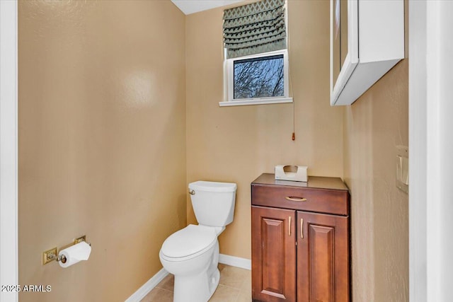 half bathroom with toilet, tile patterned flooring, and baseboards