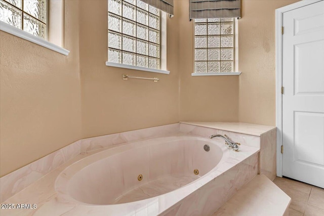 full bathroom featuring a jetted tub, plenty of natural light, and tile patterned flooring