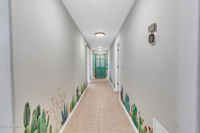 corridor featuring light tile patterned floors, visible vents, and baseboards