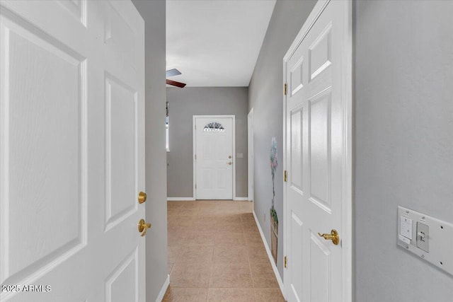 hallway featuring light tile patterned floors and baseboards