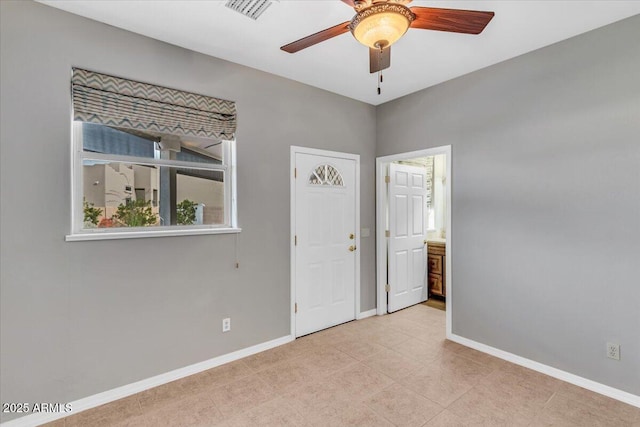 empty room featuring a ceiling fan, visible vents, and baseboards