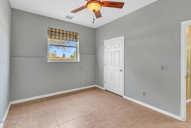 spare room with light tile patterned floors, a ceiling fan, visible vents, and baseboards