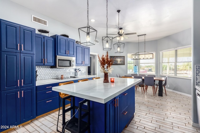 kitchen featuring a center island, blue cabinets, hanging light fixtures, and ceiling fan