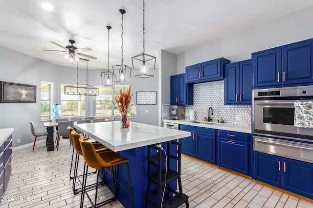 kitchen featuring stainless steel appliances, blue cabinets, sink, a kitchen island, and a breakfast bar area