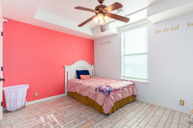 bedroom with ceiling fan and a raised ceiling