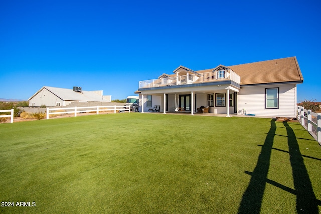 back of property featuring a yard, a patio area, and a balcony