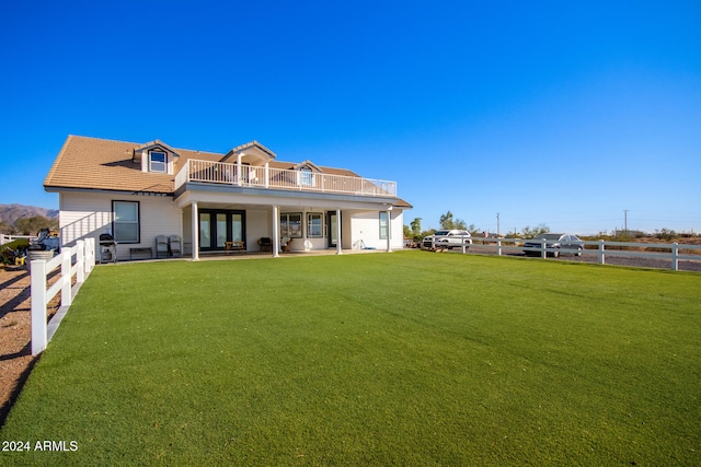 rear view of property with a yard, a balcony, and a patio area