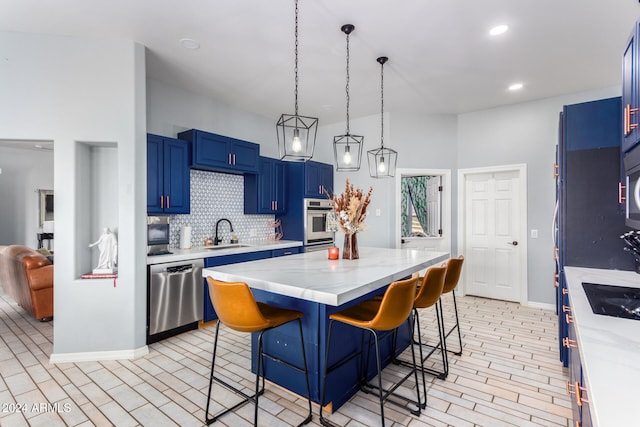 kitchen with a kitchen breakfast bar, blue cabinets, sink, a kitchen island, and stainless steel appliances