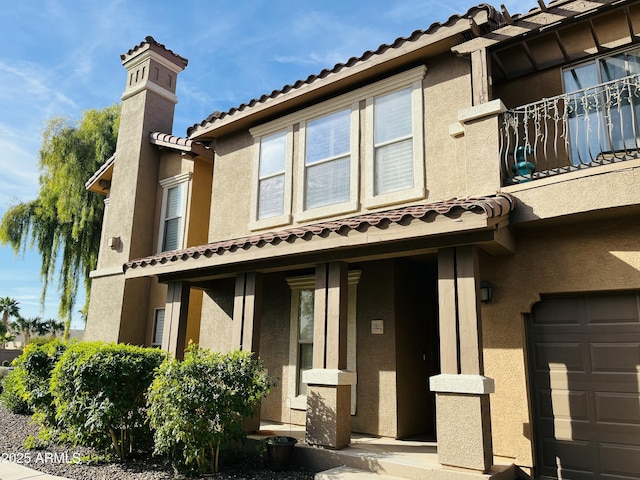 view of front of home with stucco siding, a chimney, and a tiled roof